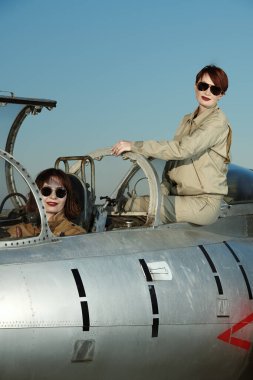 Professional commercial pilots women wearing uniform and sunglasses pose sitting in their aircraft cockpit before taking off. Women in aviation. clipart