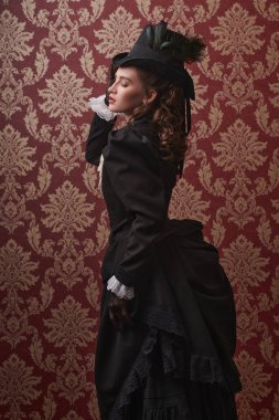 19. yüzyıldan kalma zarif bir takım elbiseli ve klasik bir arka planda poz veren güzel bir genç bayanın portresi. 19. yüzyıl moda ve güzelliği.