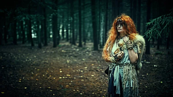 Karanlık, kasvetli bir ormanda gözlerini kapatan gizemli bir orman cadısı. Kadın şaman. Paganizm. Ölüm ritüeli. Cadılar Bayramı. Boşluğu kopyala.