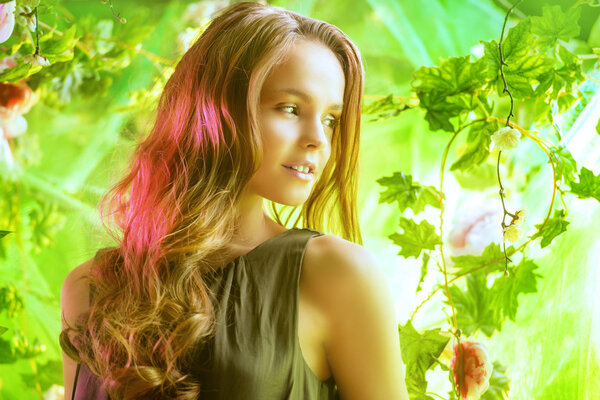 Beautiful young woman among tropical plants and flowers. Beauty, fashion. Spa, healthcare.