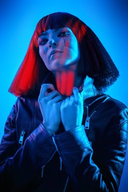 Siber punk konsepti. Parlak kırmızı makyajlı, kızıl saçlı, siyah ışıkta poz veren güzel bir siber punk kızı portresi. Sanal oyunlar. Makyaj ve saç stili. 