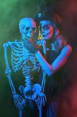 Calavera Catrina 'nın Ölüler Günü için geleneksel görünüşü. Güzel Kafatası Şeker kız gizemli kırmızı ve mavi ışıklı bir iskeletle tango yapıyor. Dia de los Muertos. Cadılar Bayramı.