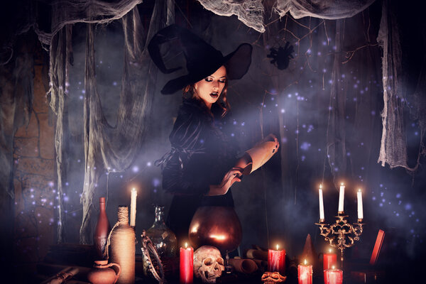 Attractive witch conjures in the wizarding lair. Fairytales. Halloween.