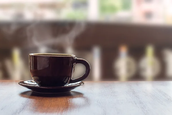 Koffiekopje op houten tafel met achtergrond in café wazig. — Stockfoto