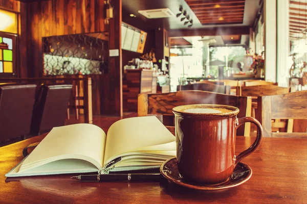 Coffee cup with open notebook on table in cafe. (Vintage process — ストック写真