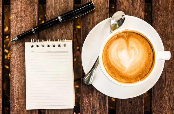 Abra um caderno branco em branco, caneta e xícara de café na mesa de madeira — Fotografia de Stock