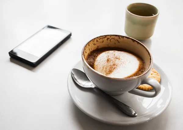 Cappuccino xícara de café e biscoito com telefone isolado no whit — Fotografia de Stock