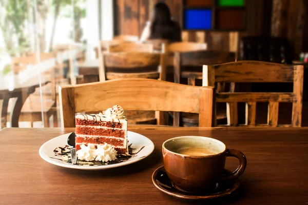 Xícara de café com fatia de bolo na mesa de madeira no café — Fotografia de Stock