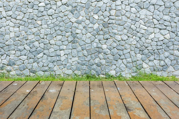 Pared de piedra y césped verde sobre fondo de madera — Foto de Stock
