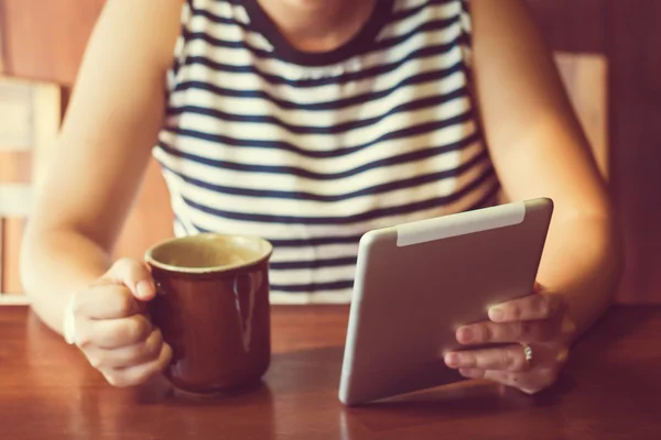 アジアの女性は、コーヒーを飲みながらカフェでタブレット コンピューターを使用して。フォーカス — ストック写真