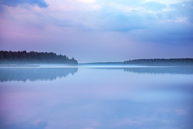 Foggy early morning sunrise on a calm mirror surfaced lake