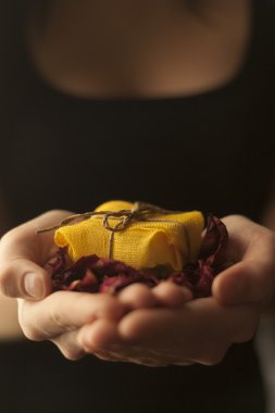 Sarı hediye kutusu sarılmış ve gül yaprakları bir kadın elinde