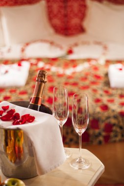 Bir tabloda bir romantik spa otel odasında şarap, şampanya bardağı ve gül yaprakları kıvılcım.