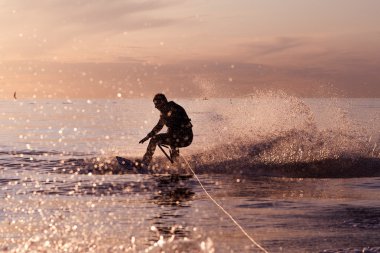Wakeboard ride on tranquil waters at a sunset clipart