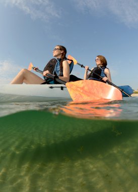 Mavi kayık içinde gülümseyen iki genç kadın 