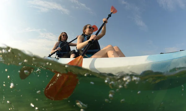 Två unga kvinnor paddling blå kajak — Stockfoto