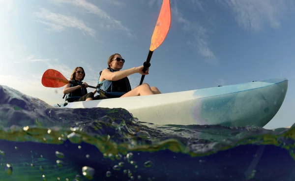 Mulheres sorrindo em caiaque azul no oceano tropical Imagem De Stock