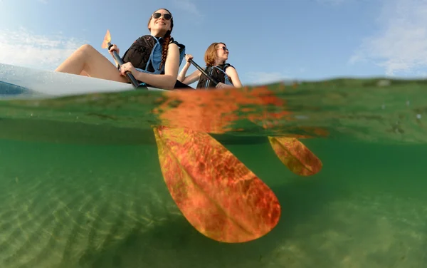 Twee jonge vrouwen die glimlachen in blauwe kajak — Stockfoto