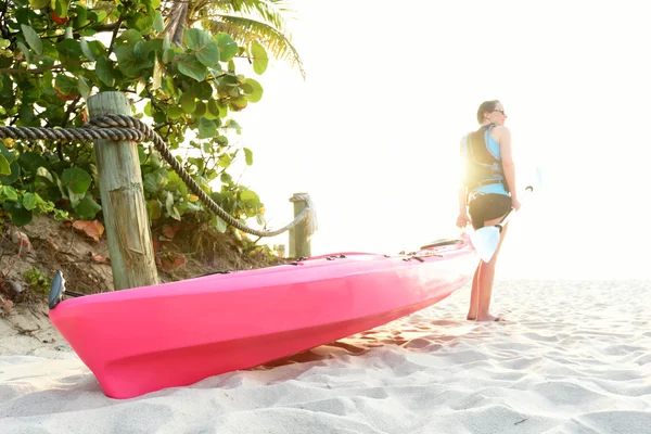 Vrouw op strand met roze kayak — Stockfoto