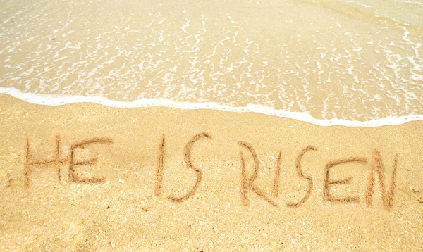 Ele ressuscitou escrito na areia para a Páscoa. — Fotografia de Stock