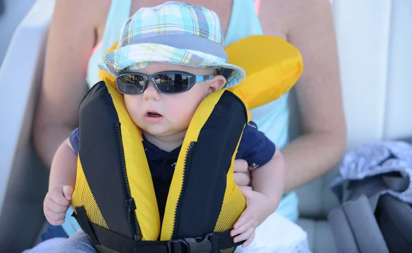 Baby mit Schwimmweste, die mit Sonnenbrille verschlossen werden muss lizenzfreie Stockbilder