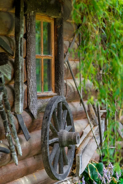 Rueda de un carro viejo cerca de casa rural de madera —  Fotos de Stock