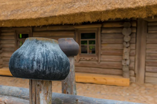 Cast iron pots on a fence near a wooden farmhouse — Stock Photo, Image