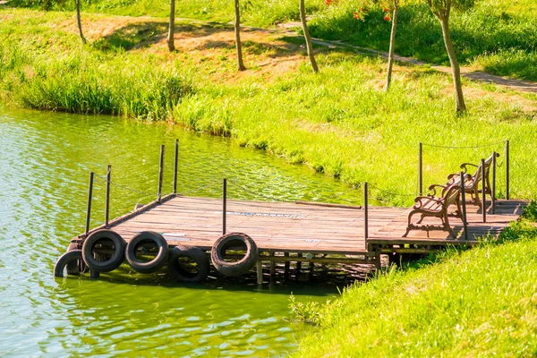 Old wooden pier on the pond with green water — Stock Photo, Image
