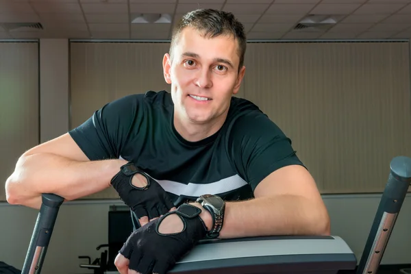 Forte giovane in palestra su un simulatore in posa — Foto Stock