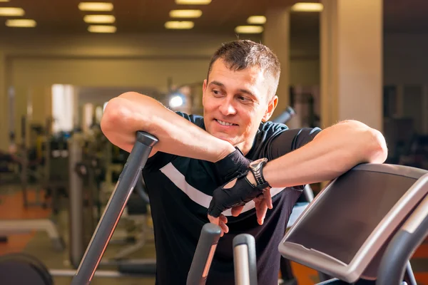 Handsome adult man in the gym resting near simulator — Stock Photo, Image