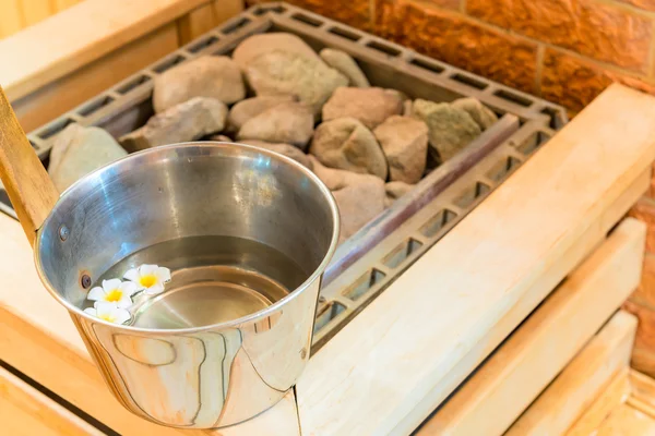 Water with floating flowers and stones in the sauna — Stock Photo, Image