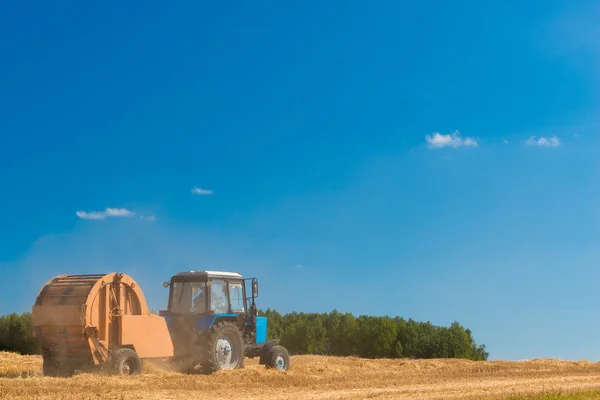 Tractor on the field to collect the cut hay to roll — Stock Photo, Image