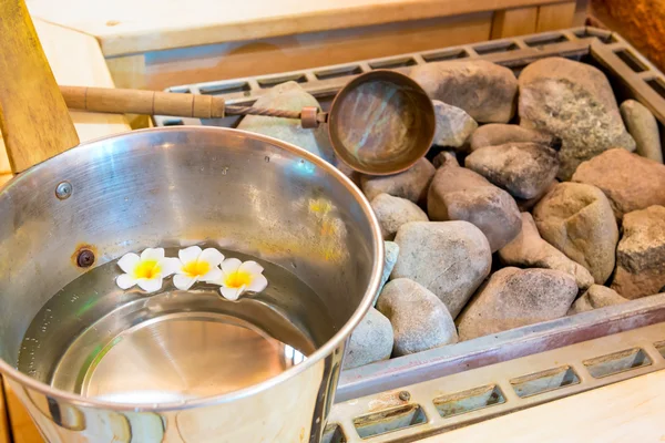 Hot stones in the sauna and a bucket of water close-up — Stock Photo, Image