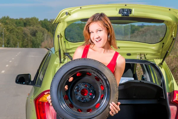 Portrait of a beautiful girl holding a spare wheel of a car — Stock Photo, Image