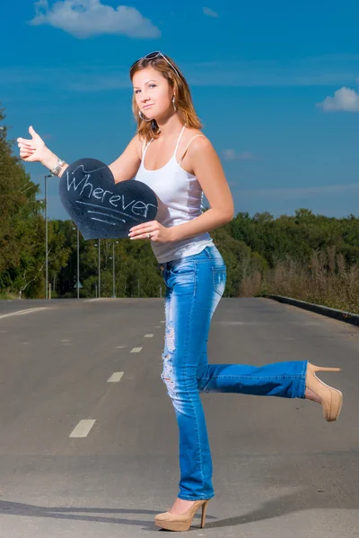 Woman in jeans and t-shirt of 30 years old travels hitchhiking — Stock Photo, Image