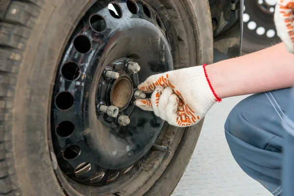 Hand in Handschuh schraubt die Muttern am Rad ab — Stockfoto