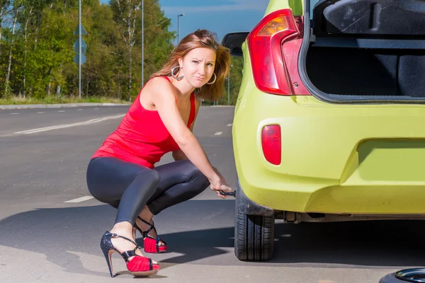 Young woman unscrews the wheel with a wrench — Stock Photo, Image