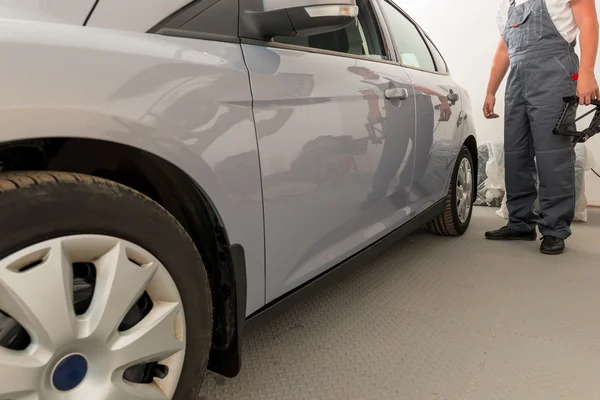 Monteur in uniform in de garage en de auto — Stockfoto