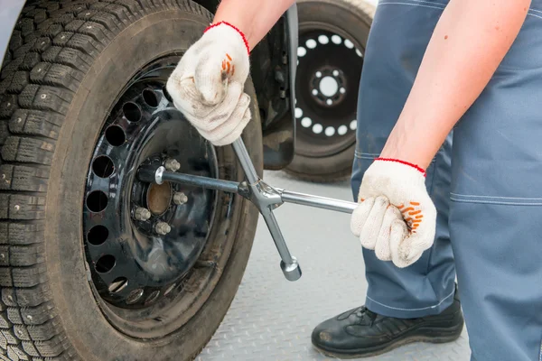 Mekaniker unscrews nötter på hjulet en skiftnyckel — Stockfoto