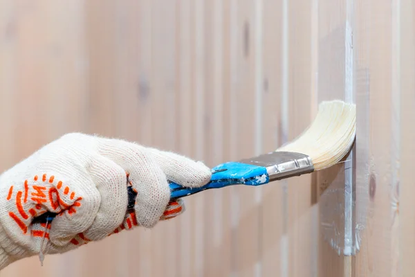 Рука об перчатку покрасить деревянную стену защитной краской — стоковое фото