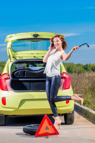 Menina alegre vai substituir a roda do carro — Fotografia de Stock