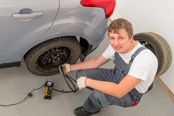 Lachende mechanic een pomp opgeblazen de het wiel in garage — Stockfoto