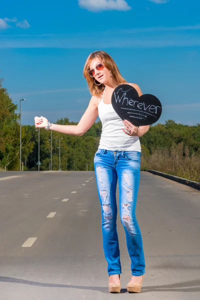 Junges Mädchen trampt auf einer Landstraße — Stockfoto