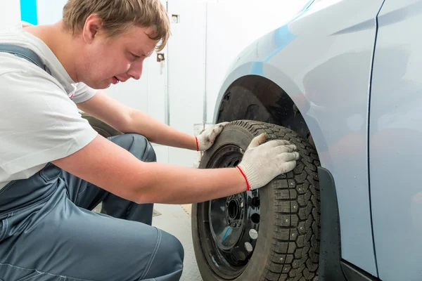 Mecánico instala en el coche neumáticos de invierno en el garaje — Foto de Stock