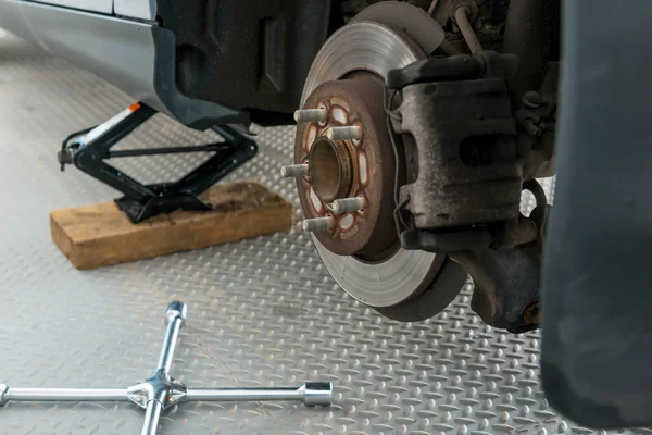 Schraubenschlüssel und Wagenheber in der Nähe des Autos in der Garage in Großaufnahme — Stockfoto