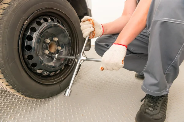 Mechaniker schraubt das Rad mit einem Schraubenschlüssel ab, Nahaufnahme — Stockfoto