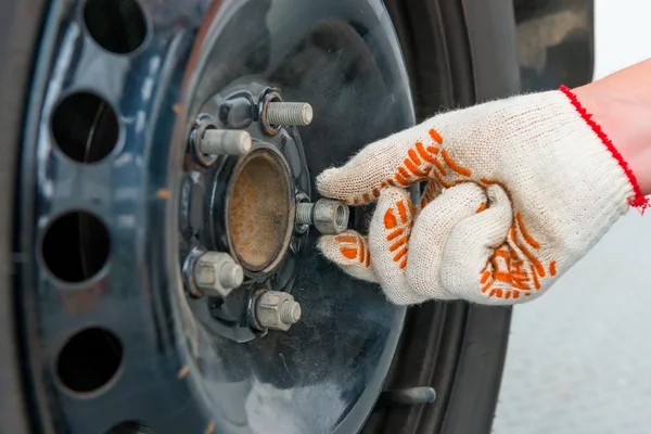 Iemands hand robotarm de noten op de auto wiel, close-up shot — Stockfoto