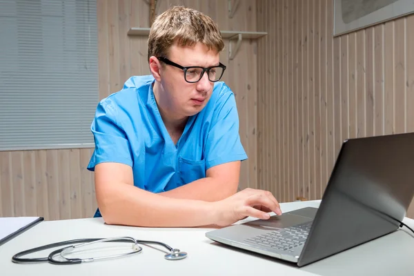 Ernstige mannelijke arts met glazen werken op de computer — Stockfoto