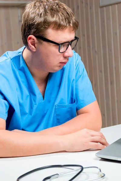 Retrato de médico pensativo em óculos em uniforme médico azul — Fotografia de Stock