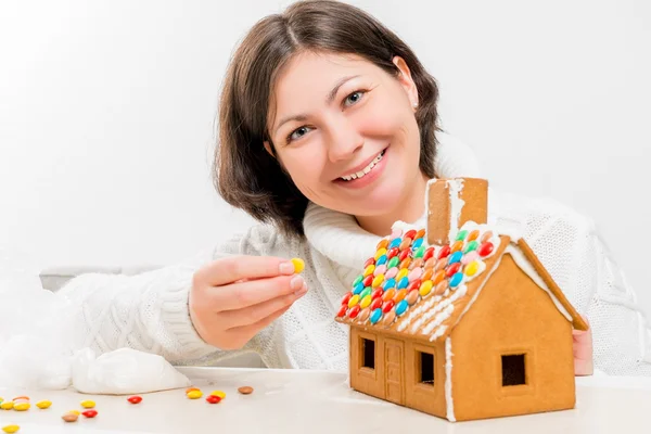 Morena feliz decorada com festivo uma casa de gengibre — Fotografia de Stock